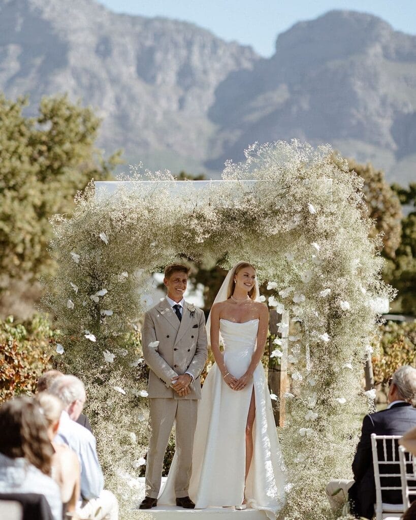 Floral arch by Okasie with the happy newlyweds underneath.